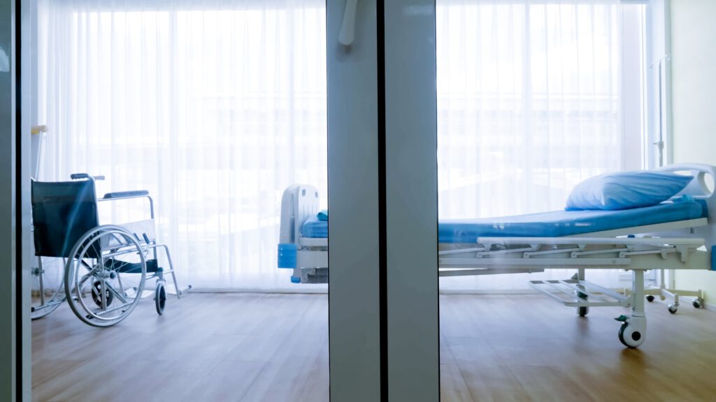 Bedroom for patient in a hospital, Empty bed and wheelchair on hospital ward.