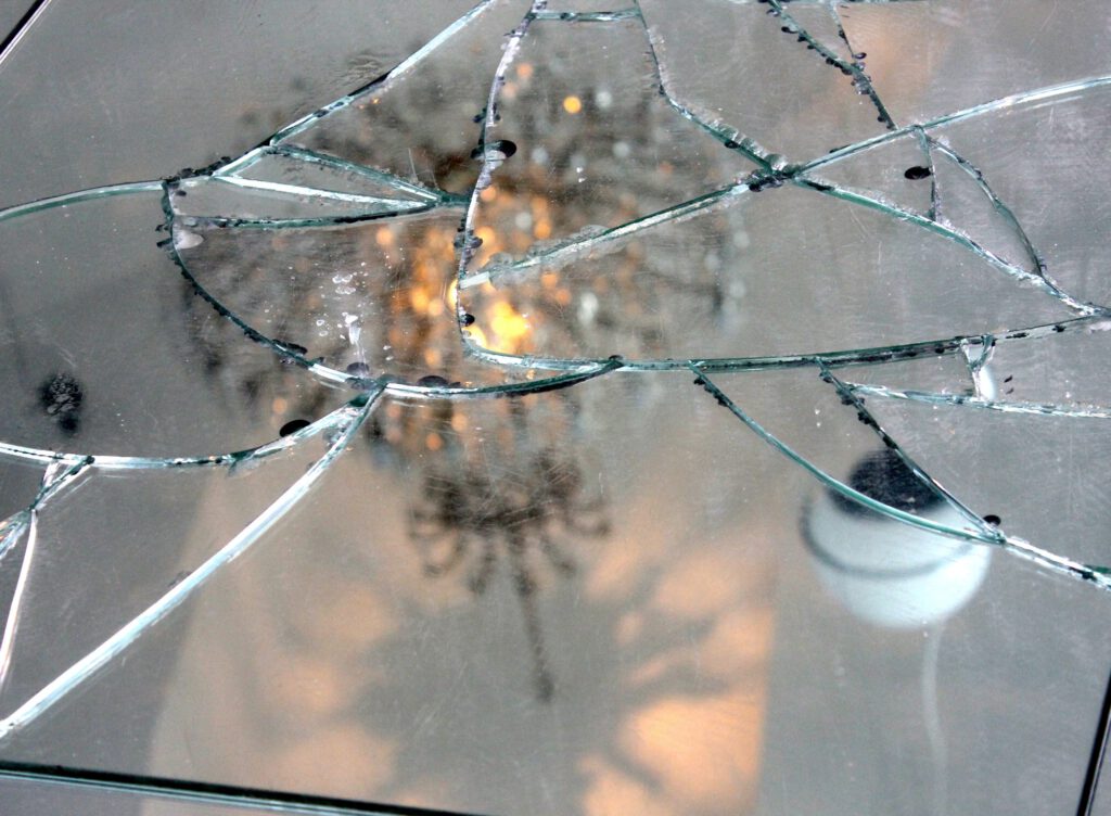 Cracked mirror with chandelier reflecting on it