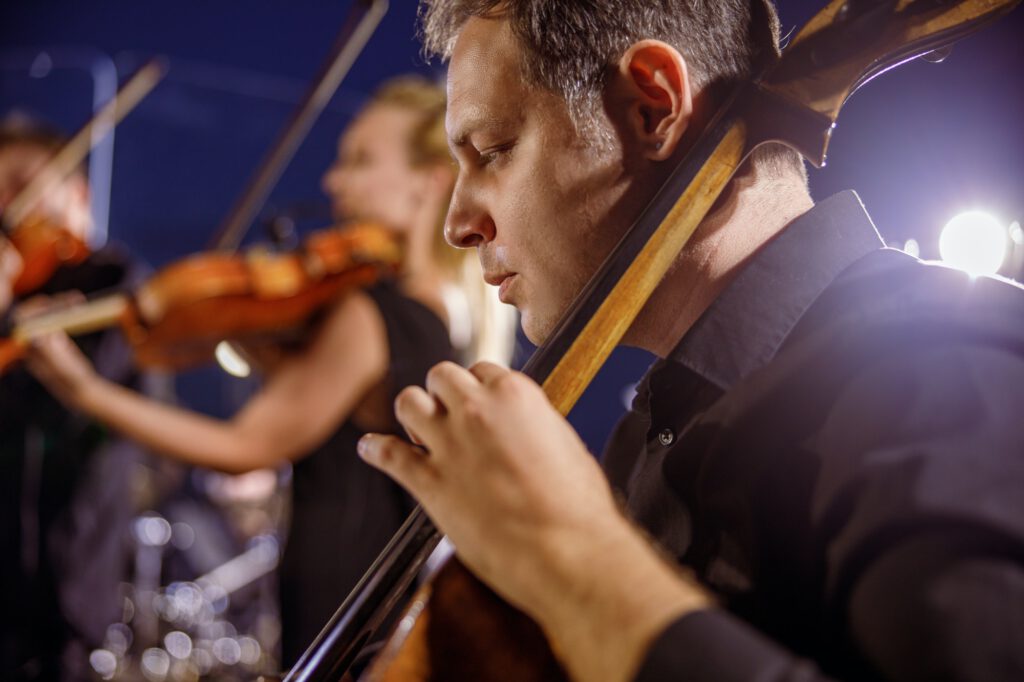 Male musician playing cello at night outdoor concert